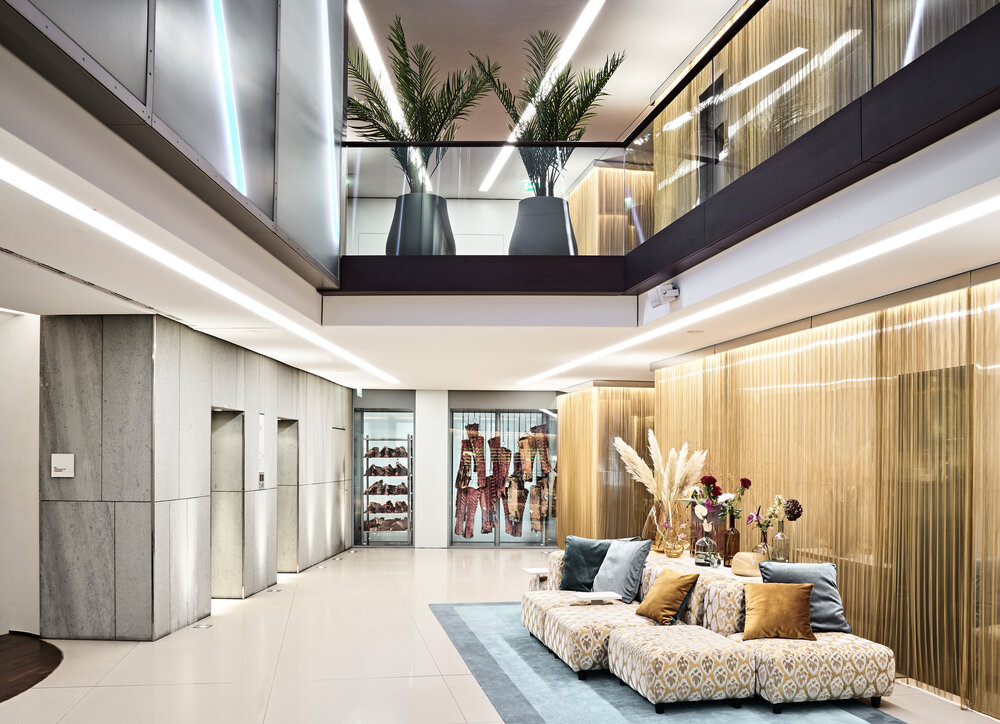 Modern lobby area featuring a plush seating arrangement, decorative plants, and soft lighting, ideal for relaxation or meetings.