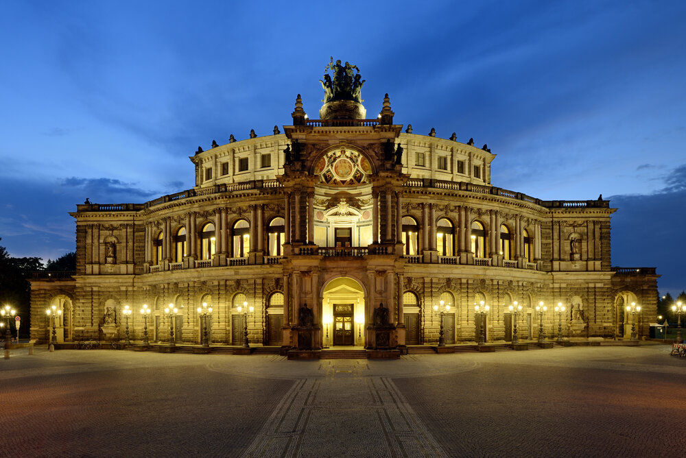 The Semperoper in Dresden illuminated at dusk, showcasing its elegant architecture against a twilight sky.