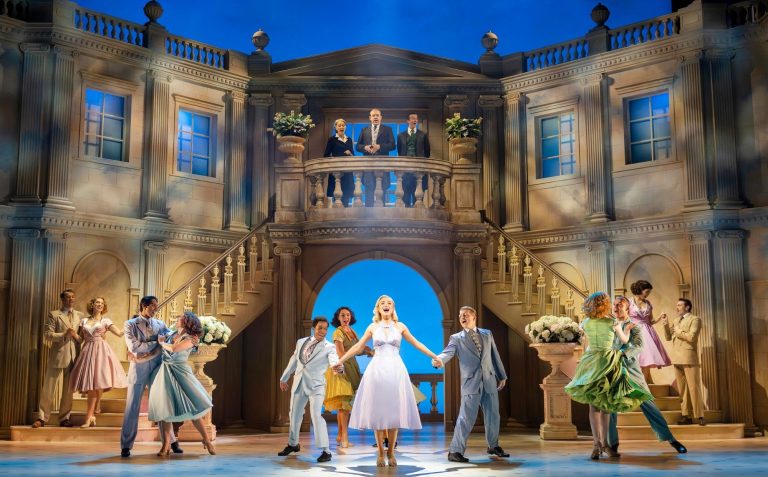A romantic dance scene from the musical "High Society" set in an elegant venue with actors in period costumes.