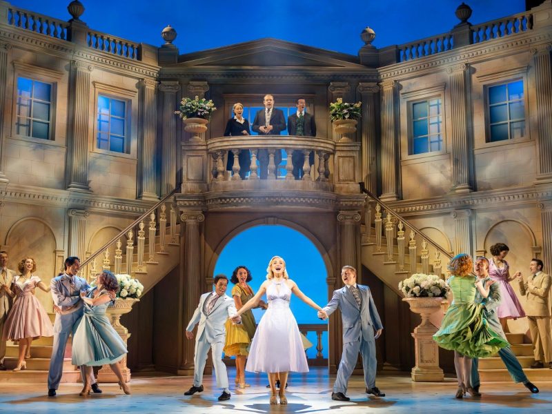 A romantic dance scene from the musical "High Society" set in an elegant venue with actors in period costumes.