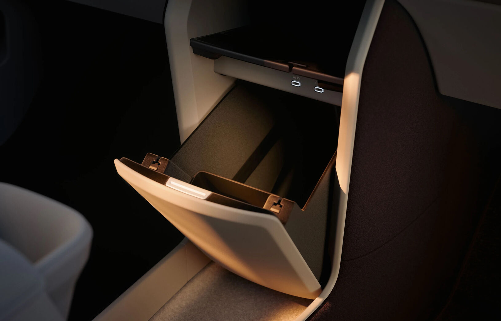 The interior storage compartment of the Volvo EX60, featuring a soft glow and USB-C ports for charging.