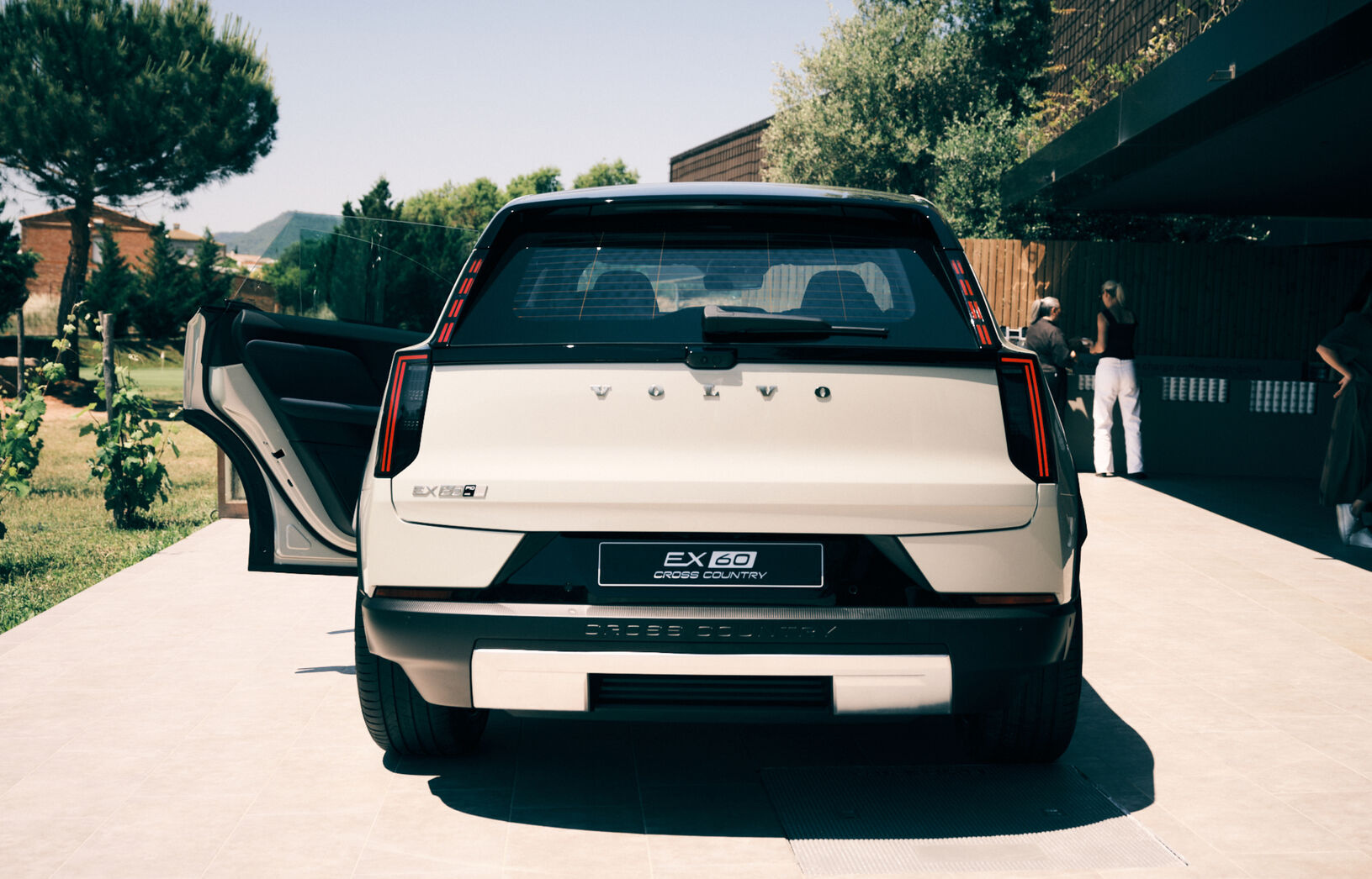 Volvo EX60 parked with rear view facing the camera, showcasing its sleek design and open rear door in an outdoor setting.