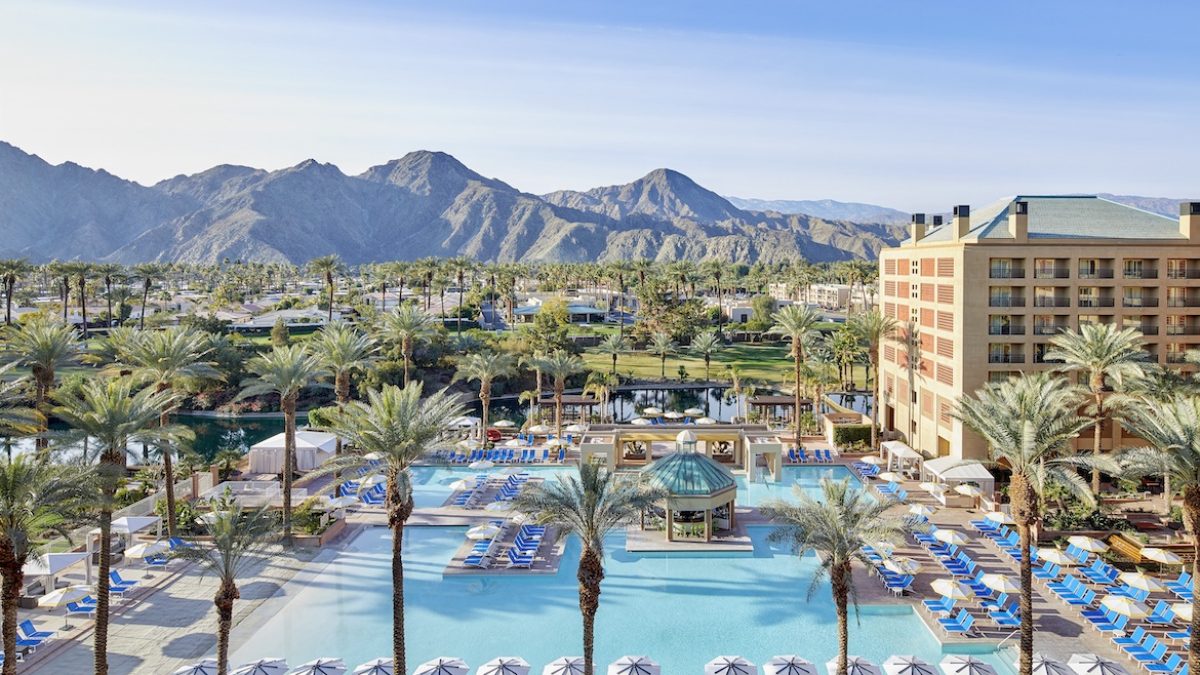 Resort pool area at Renaissance Esmeralda with palm trees, lounge chairs, and mountains in the background under a clear sky.
