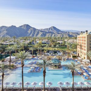 Resort pool area at Renaissance Esmeralda with palm trees, lounge chairs, and mountains in the background under a clear sky.