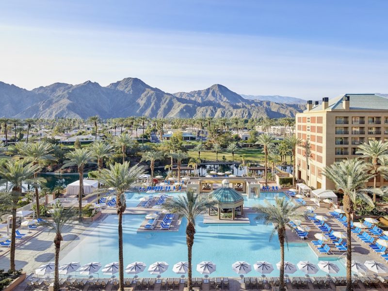 Resort pool area at Renaissance Esmeralda with palm trees, lounge chairs, and mountains in the background under a clear sky.