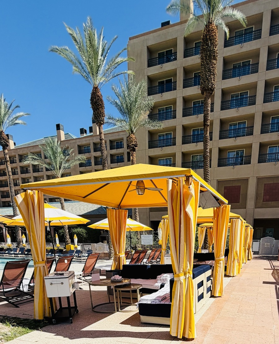 Yellow cabanas and lounge chairs surround a pool at the Renaissance Esmeralda Resort & Spa under a clear blue sky.
