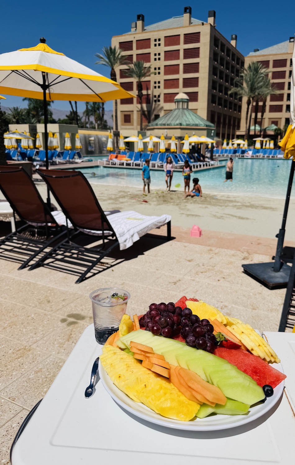Fresh fruit platter with a variety of melons, pineapple, and grapes next to a pool at Renaissance Esmeralda Resort & Spa.