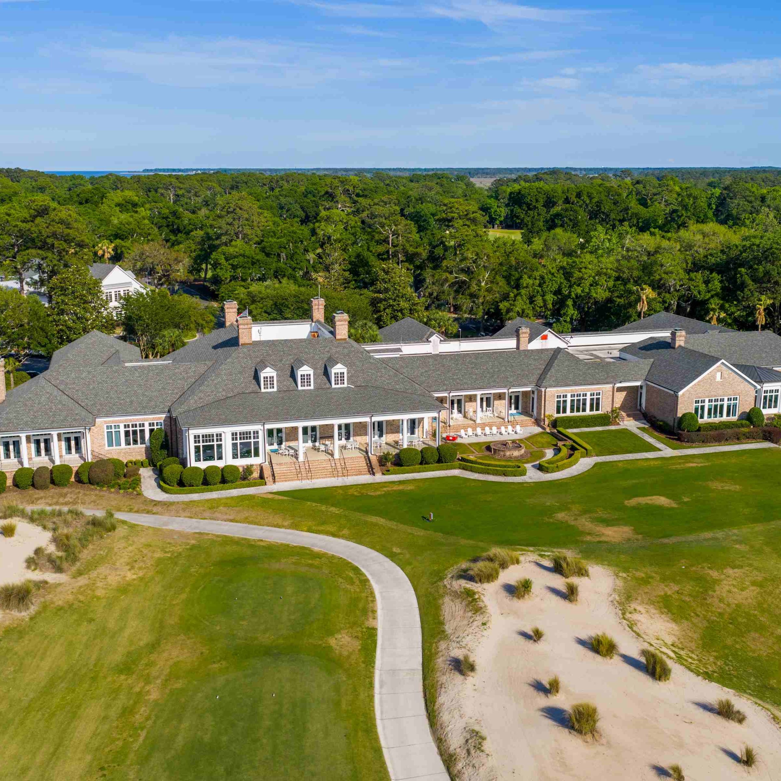 Luxury estate in Bluffton showcasing expansive lawns and elegant architecture surrounded by lush greenery and coastal views.
