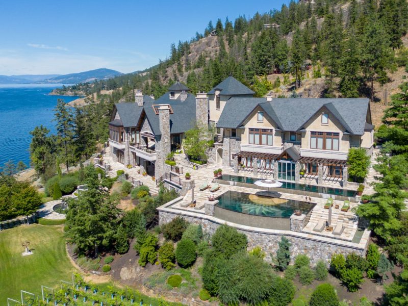Exclusive waterfront estate overlooking a serene lake, featuring elegant architecture and lush landscaping.
