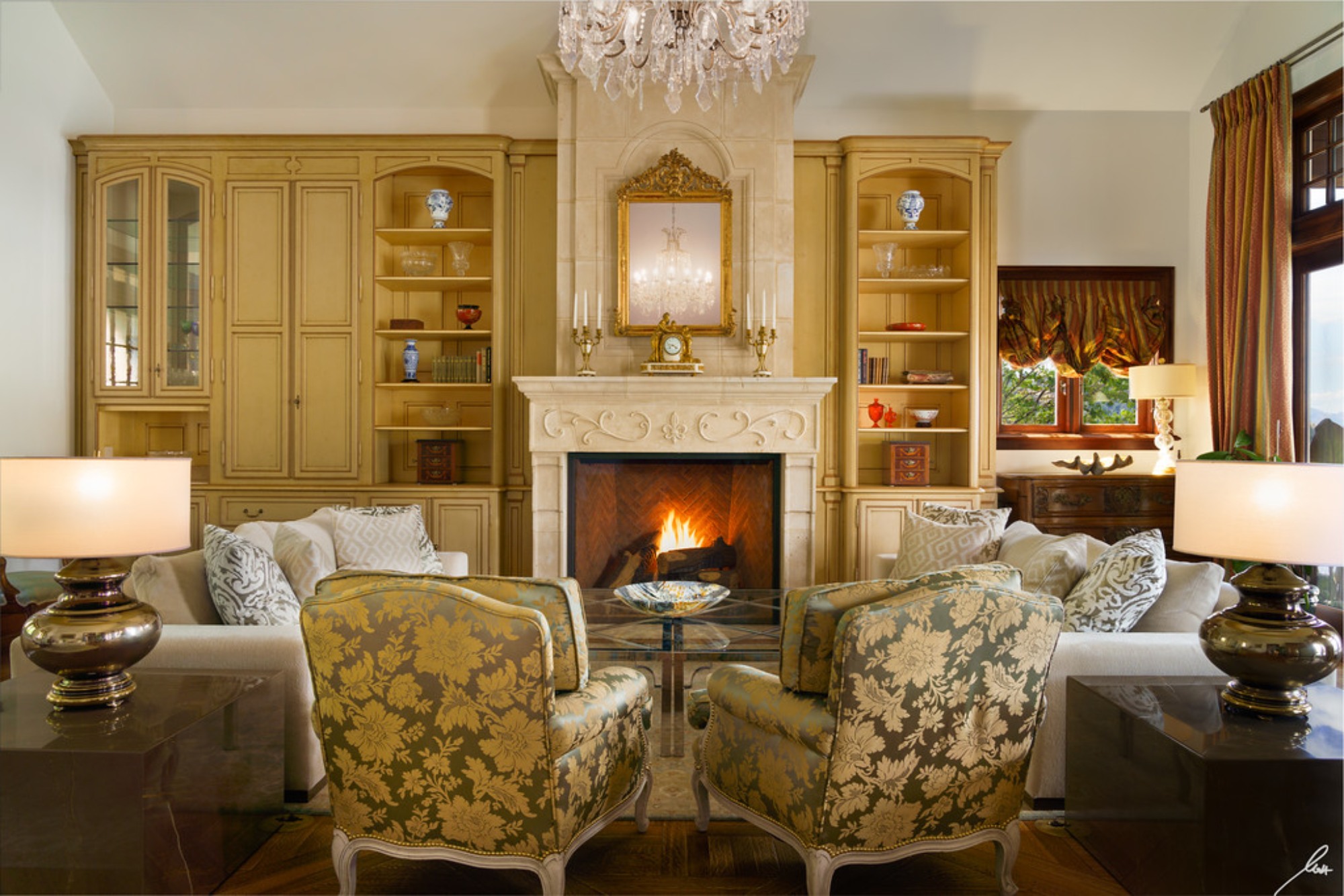 Elegant living room with floral-patterned chairs, a cozy fireplace, and built-in shelves showcasing fine decor items.