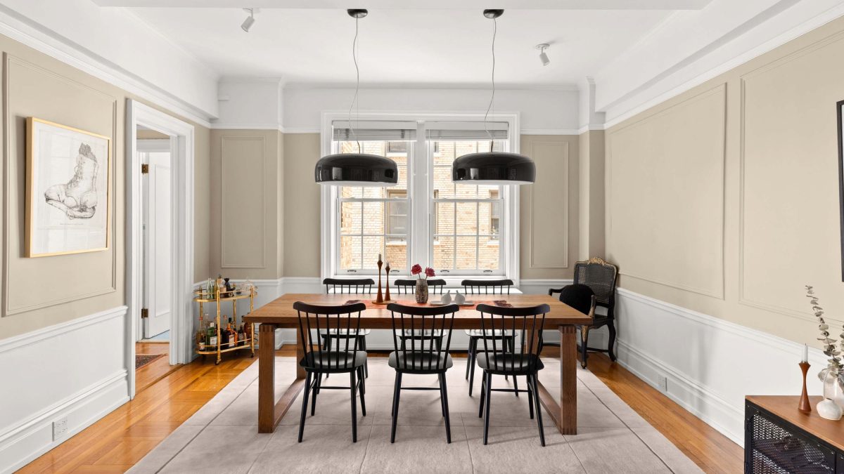 Modern dining area featuring a wooden table, black chairs, and elegant light fixtures against a soft color palette.