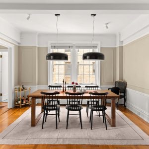 Modern dining area featuring a wooden table, black chairs, and elegant light fixtures against a soft color palette.