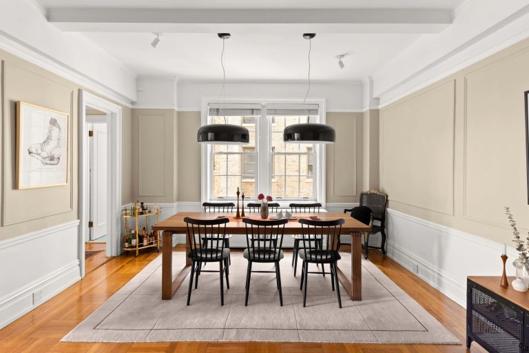 Modern dining area featuring a wooden table, black chairs, and elegant light fixtures against a soft color palette.