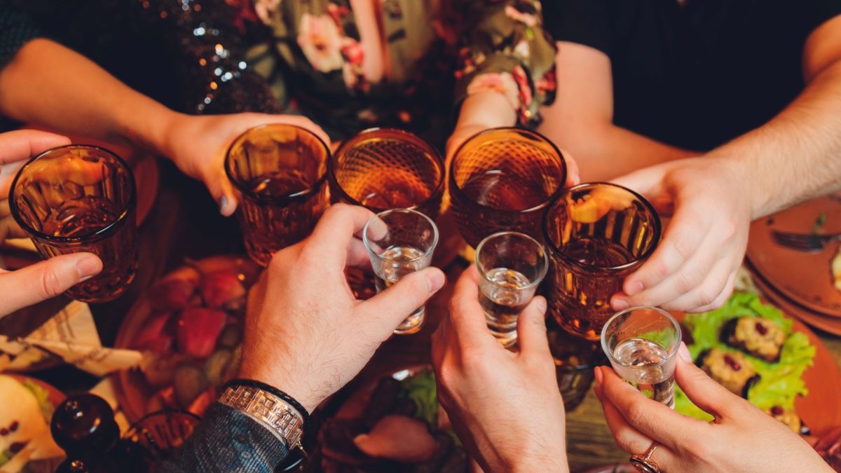 Hands clinking glasses in a toast, surrounded by food and drinks, capturing a lively bachelor party celebration.