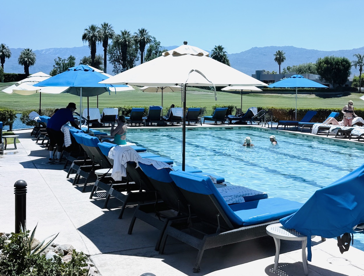 Relaxing pool area at JW Marriott Desert Springs with lounge chairs, sun umbrellas, and guests enjoying the water.