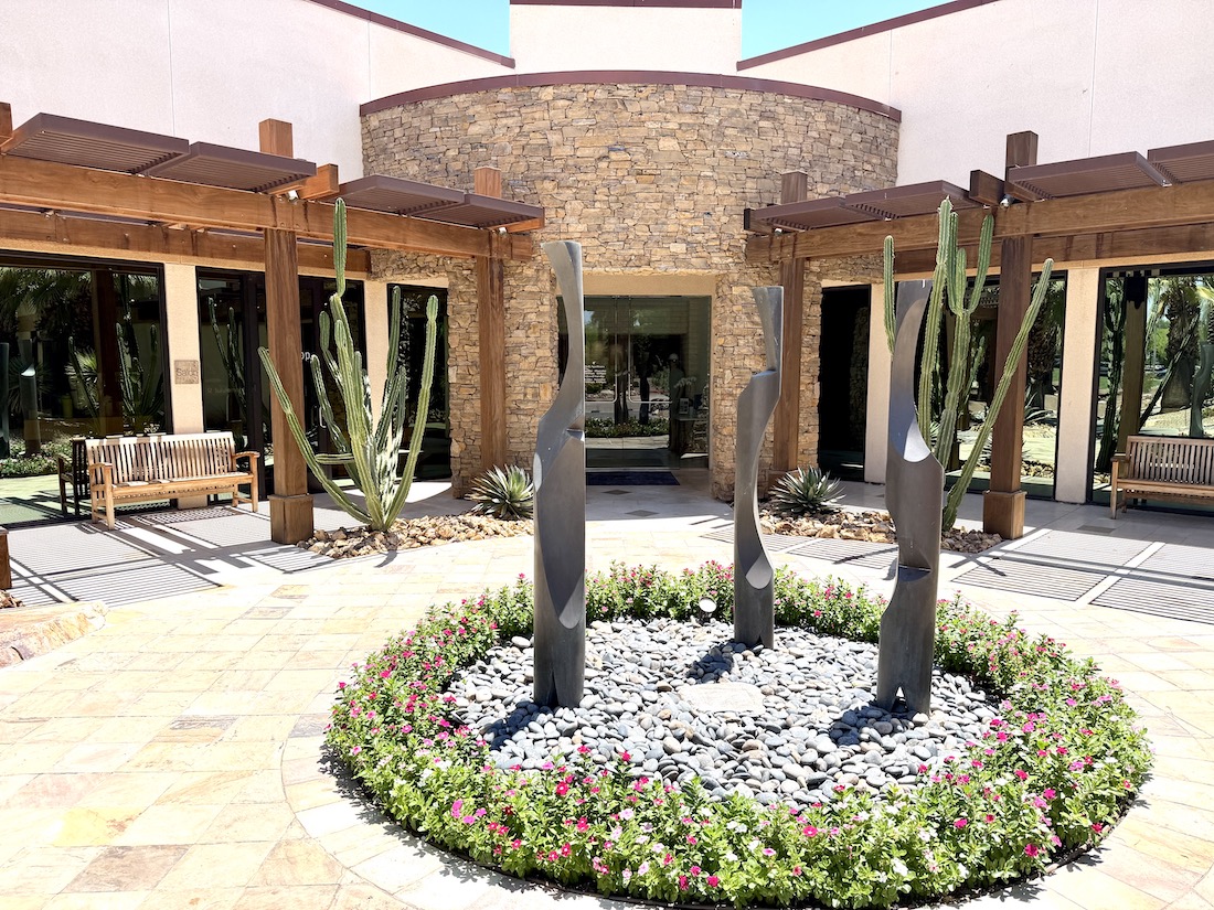 Outdoor entrance of JW Marriott Desert Springs Resort & Spa featuring sculptures, cacti, and colorful landscaping.