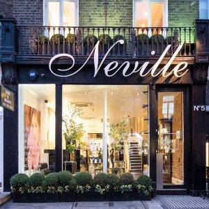 Neville Hair & Beauty storefront featuring elegant signage and lush greenery, inviting customers for hair and beauty services.