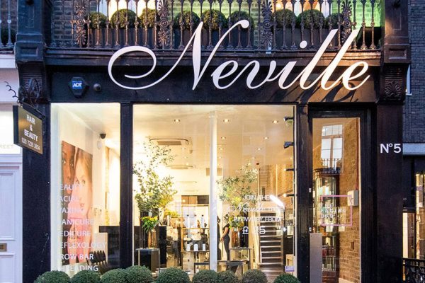 Neville Hair & Beauty storefront featuring elegant signage and lush greenery, inviting customers for hair and beauty services.