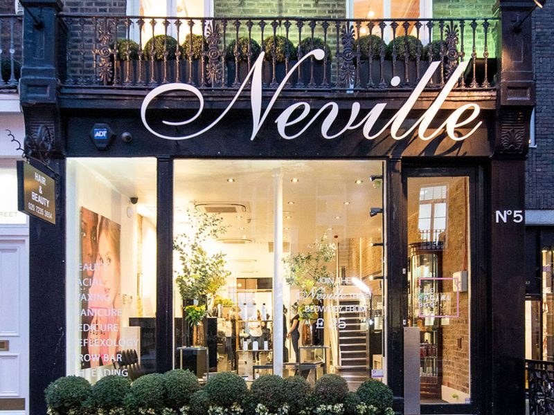 Neville Hair & Beauty storefront featuring elegant signage and lush greenery, inviting customers for hair and beauty services.