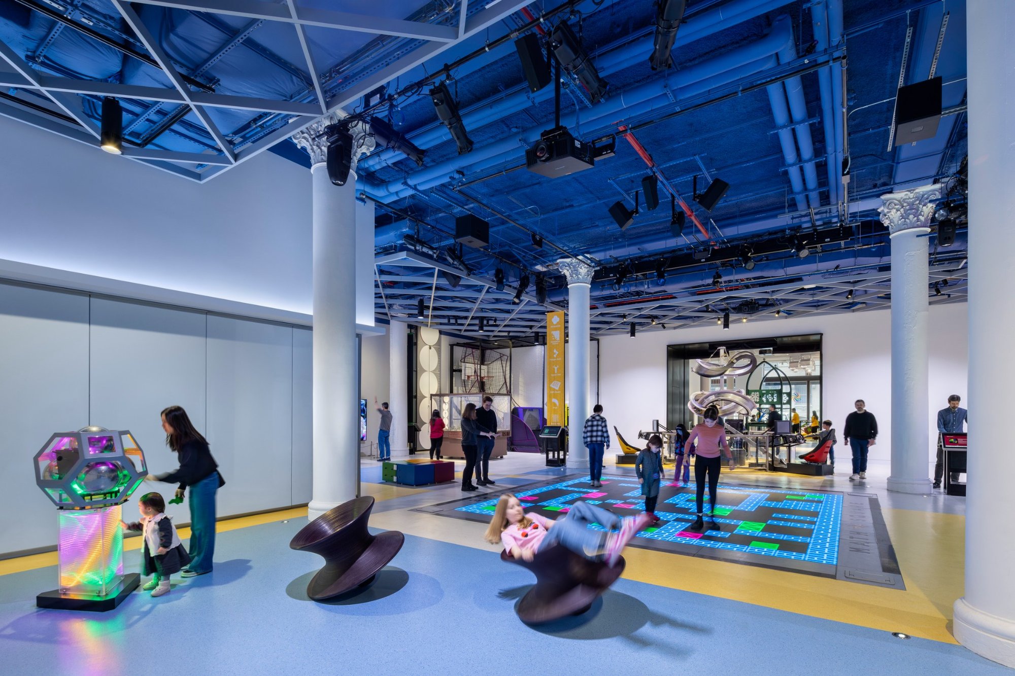 Visitors explore interactive exhibits in the Central Gallery of the National Museum of Mathematics, surrounded by colorful displays.
