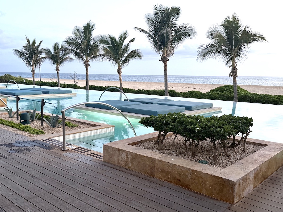 Infinity pool at Nobu Los Cabos surrounded by palm trees and beach, offering a tranquil luxury environment.