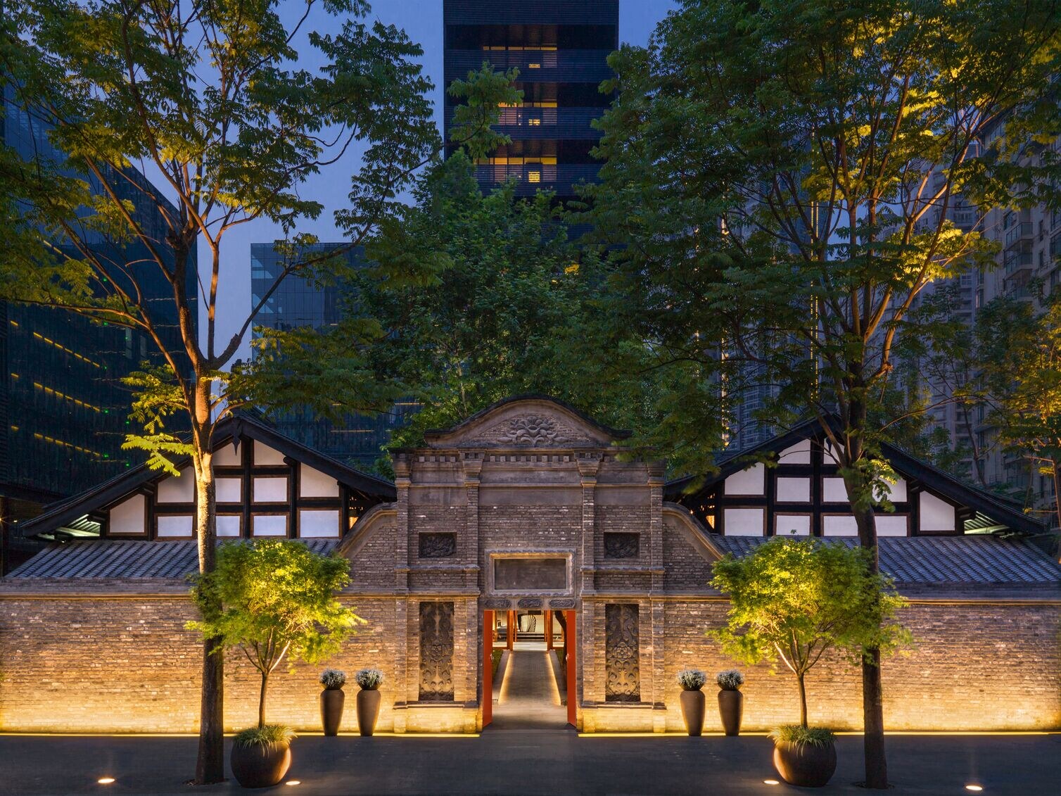 Historic architecture illuminated at night, surrounded by trees and modern buildings in Chengdu.