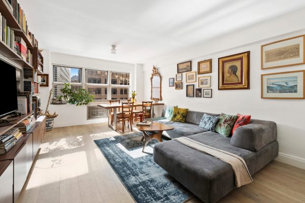 Spacious living area featuring a gray sectional sofa, dining table, wall art, and large windows with city views.