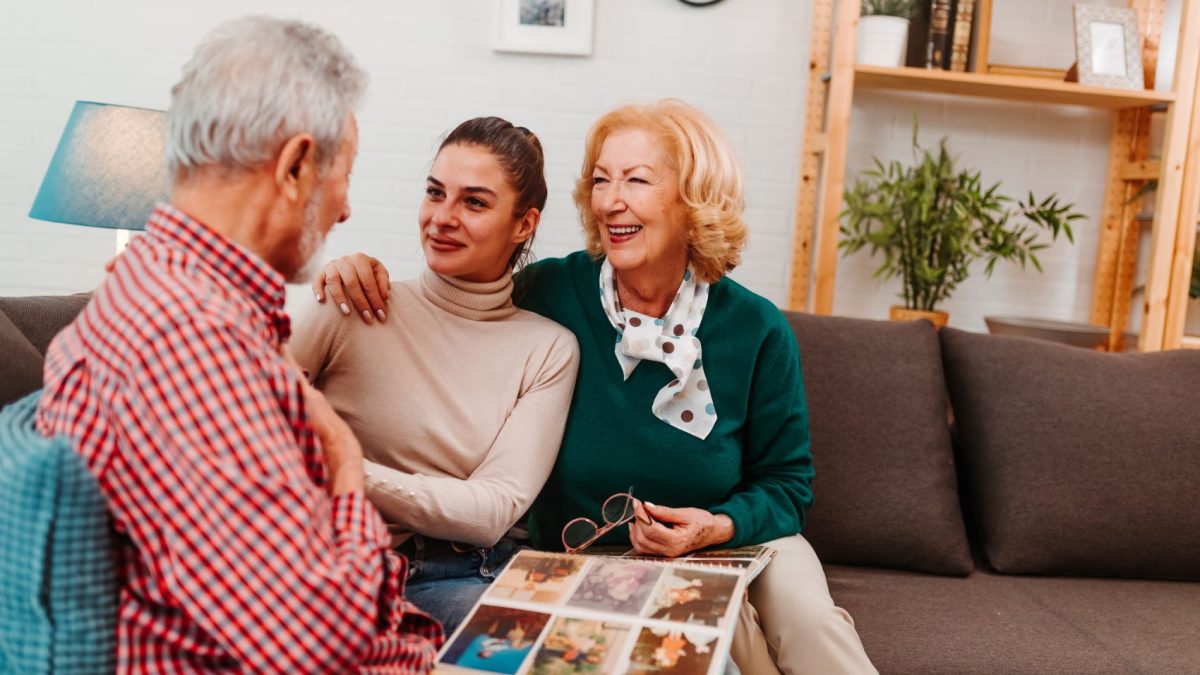 Three generations of family enjoy sharing memories while looking through a photo album in a cozy living room setting.
