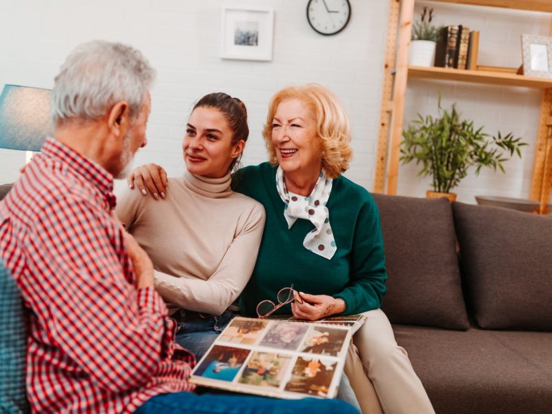 Three generations of family enjoy sharing memories while looking through a photo album in a cozy living room setting.