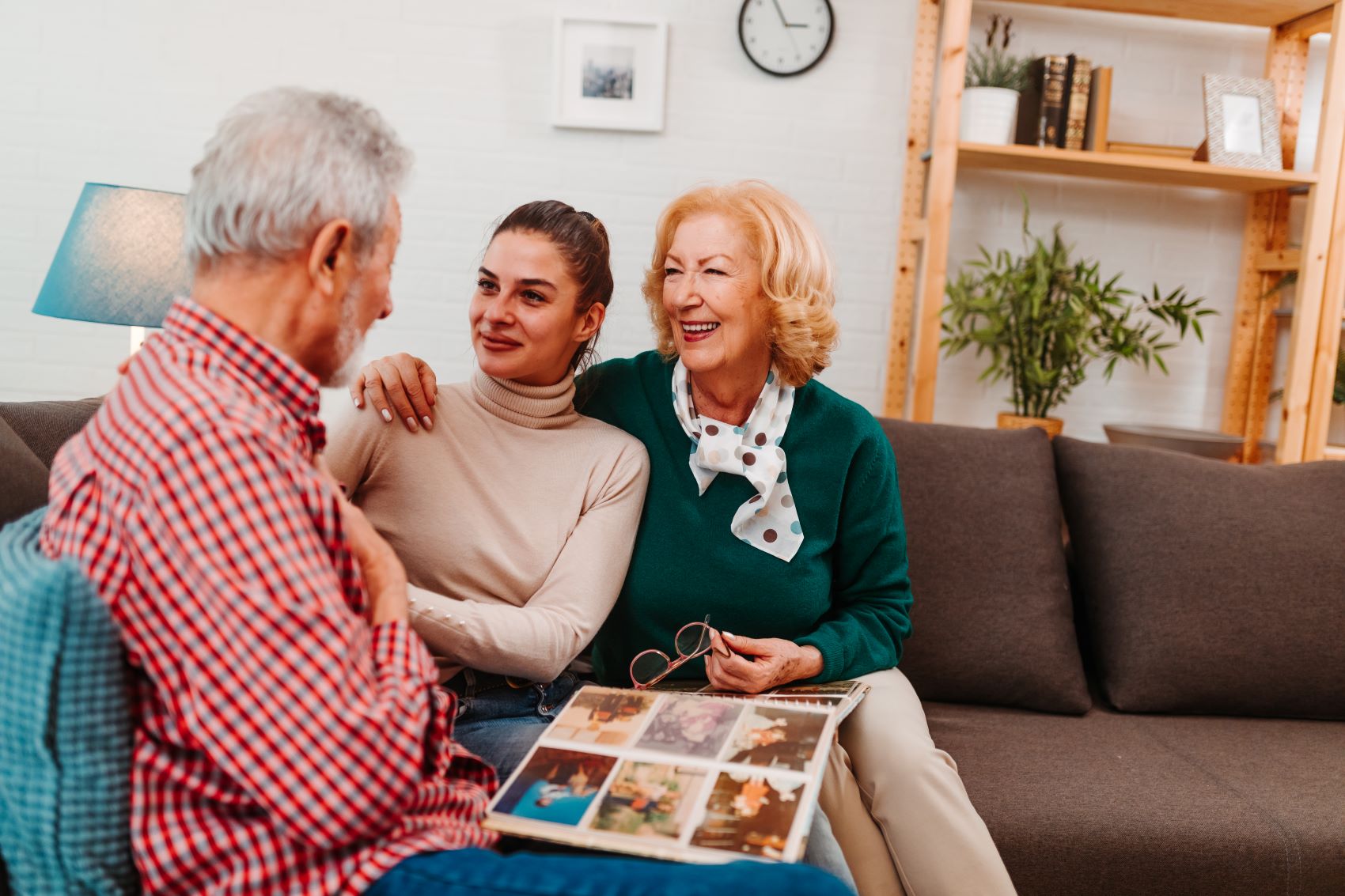 Three generations of family enjoy sharing memories while looking through a photo album in a cozy living room setting.