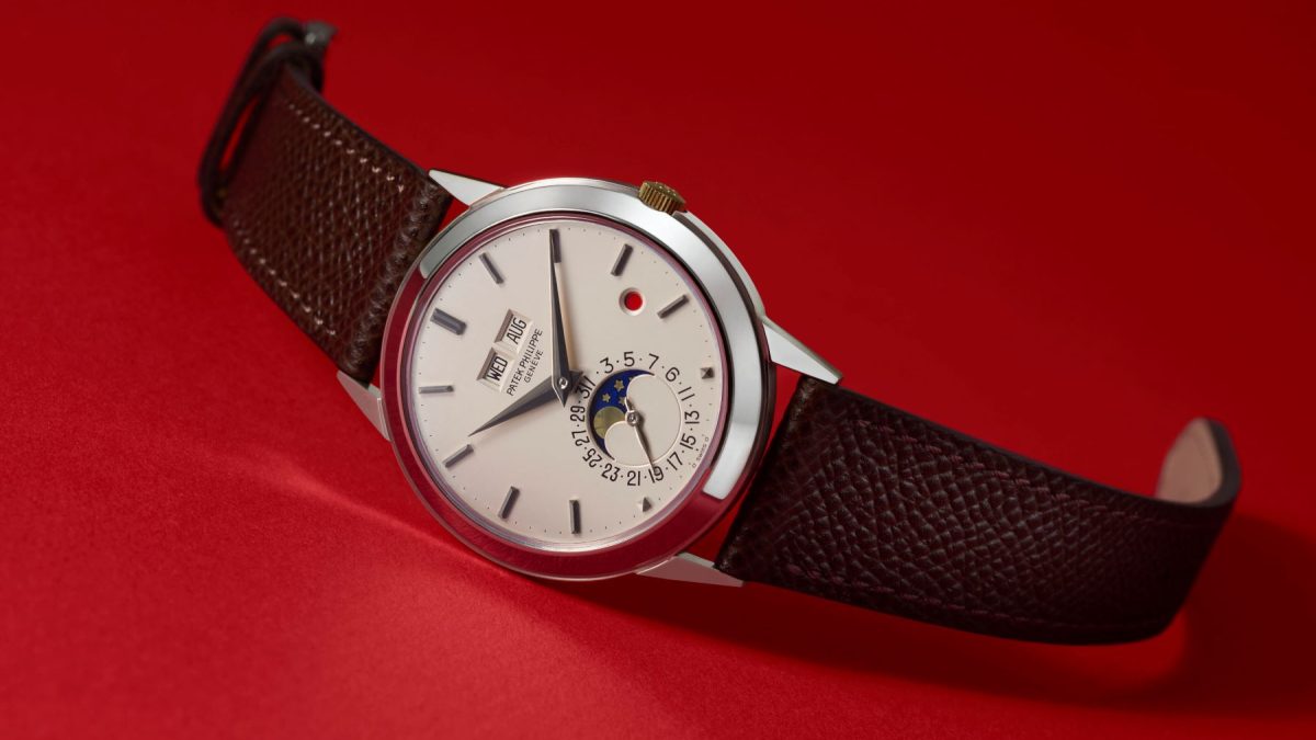 Patek Philippe watch featuring a silver dial with date and moon phase display, set on a dark brown leather strap.