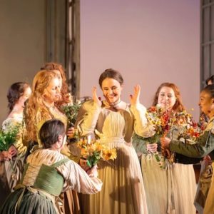 A joyful scene from The Marriage of Figaro at the Royal Opera House, featuring performers celebrating with flowers.