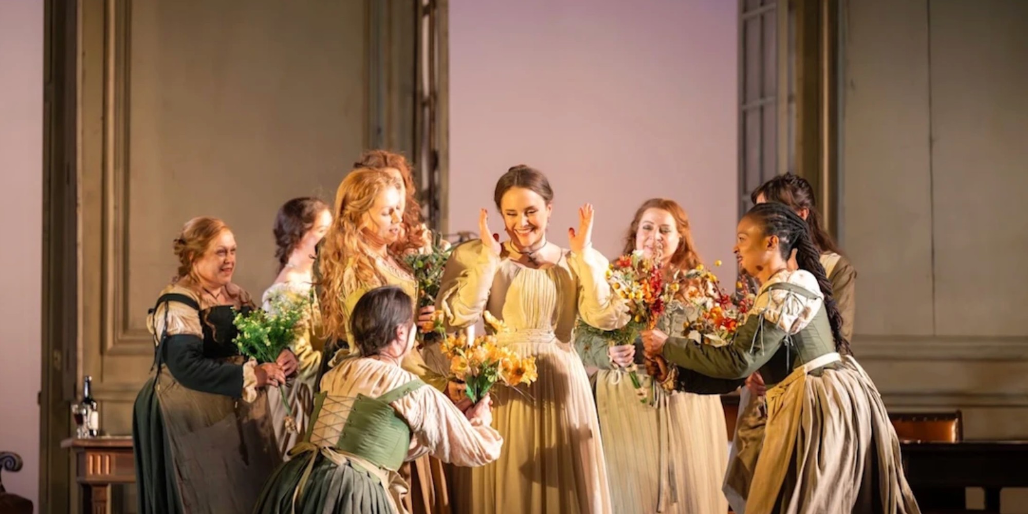 A joyful scene from The Marriage of Figaro at the Royal Opera House, featuring performers celebrating with flowers.