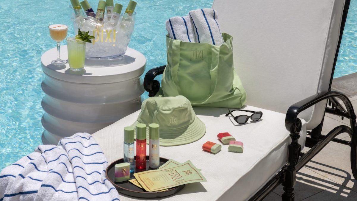 Summer glow-up essentials from Pixi Beauty by the pool, featuring products, drinks, and a green bag on a lounge chair.