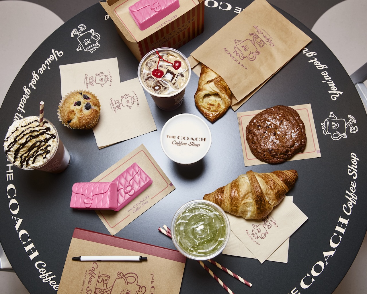 Overview of drinks and pastries at Coach Coffee Shop, featuring a variety of coffees, croissants, and desserts on a round table.