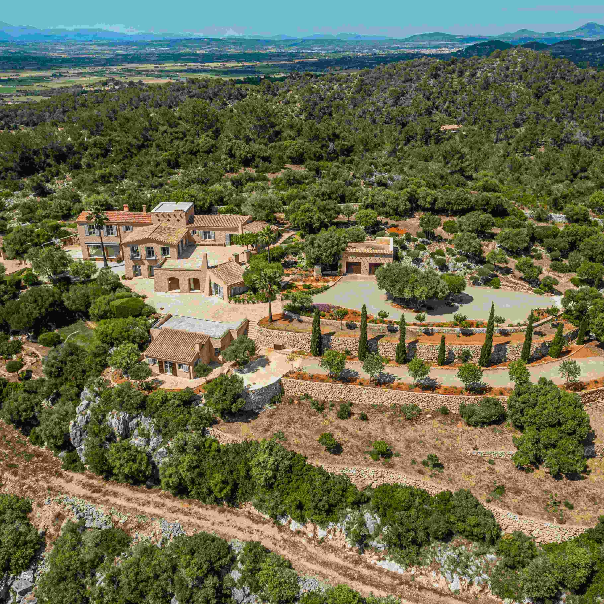 Mallorca hilltop estate featuring panoramic views of the Mediterranean landscape with lush greenery and a swimming pool.