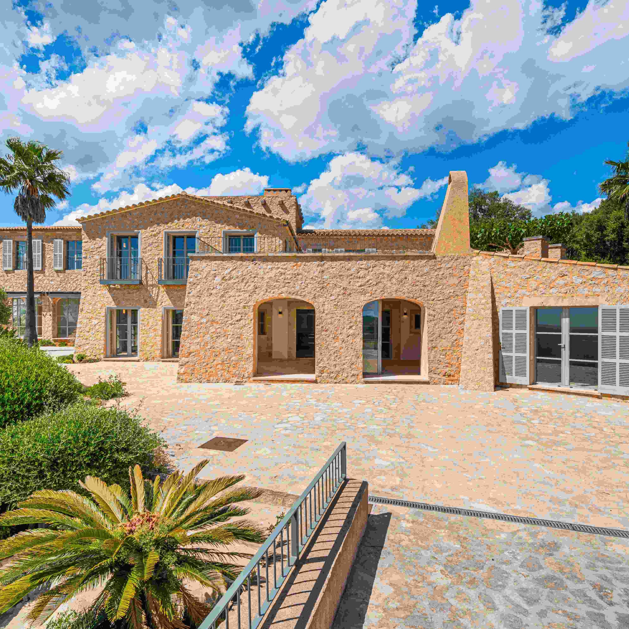 Mallorca hilltop estate featuring stone architecture, lush greenery, and panoramic views of the Mediterranean landscape.