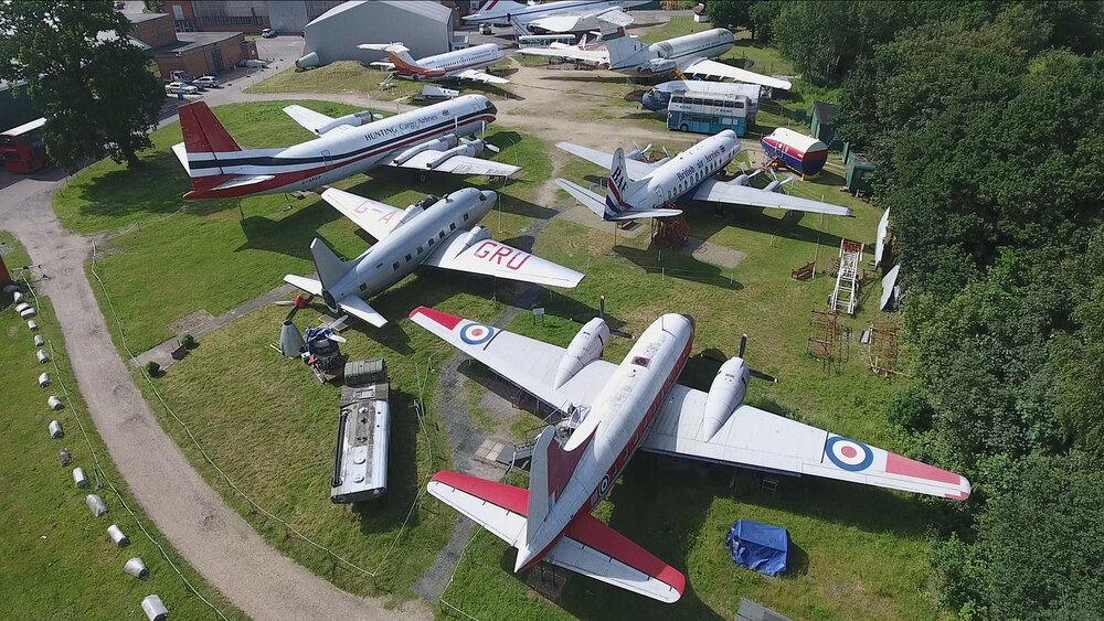 Aerial view of vintage aircraft displayed at Brooklands Museum, showcasing various models in a grassy area.