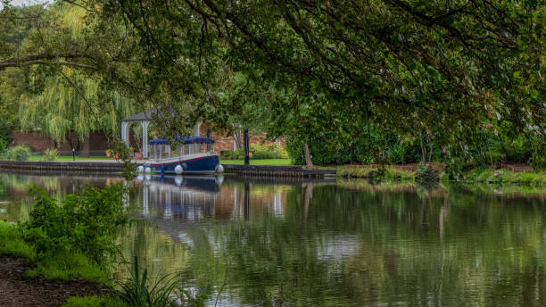 A tranquil view of a canal in Weybridge, lined with lush greenery and a boat moored along the peaceful waters.