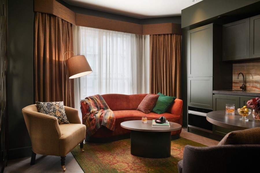 Cozy living room with a curved sofa, armchair, and modern decor highlighted by natural light and warm colors.