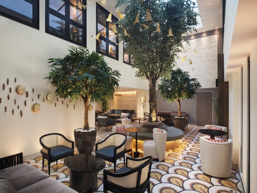 Elegant lounge area featuring large plants and stylish seating, illuminated by natural light in a chic atmosphere.