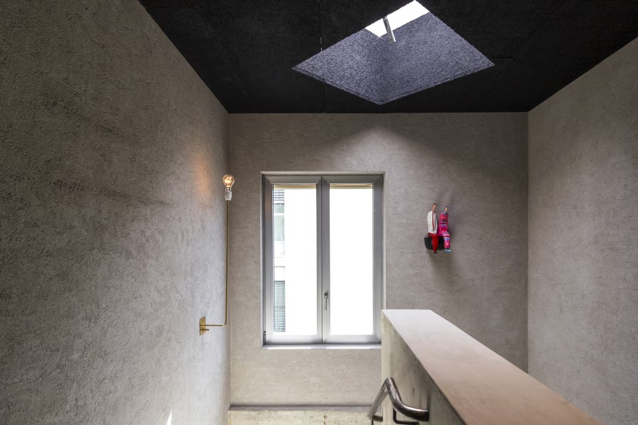 Modern stairwell featuring a skylight, large window, textured walls, and a decorative wall hanging in B5 Boutique Hotel Lugano.