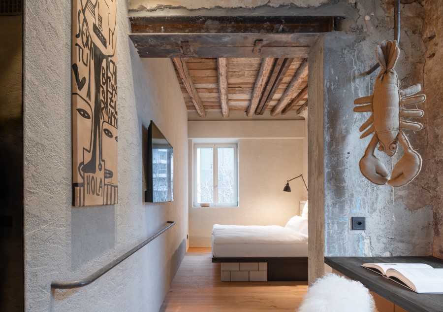 Stylish interior of a hotel room featuring rustic beams, modern furnishings, and artwork on the walls.