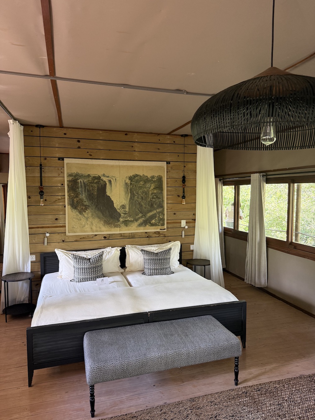 Stylish bedroom in Zambia featuring a large bed, decorative pillows, natural light, and wooden accents.