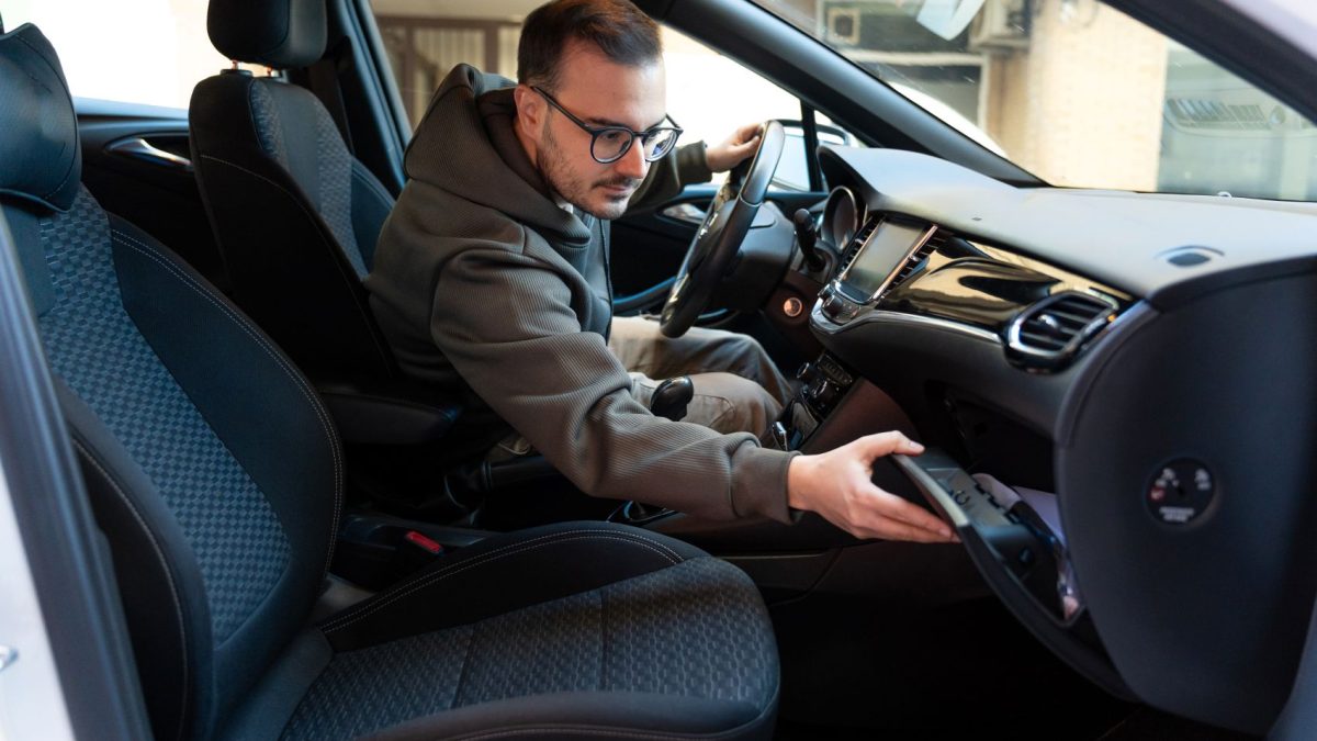 A person reaching for an item in the glove compartment of a car's interior.