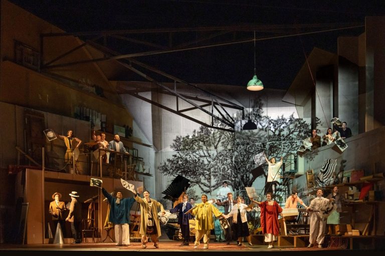A vibrant scene from L'Orfeo at Glyndebourne, featuring performers in colorful costumes on stage with a dramatic backdrop.