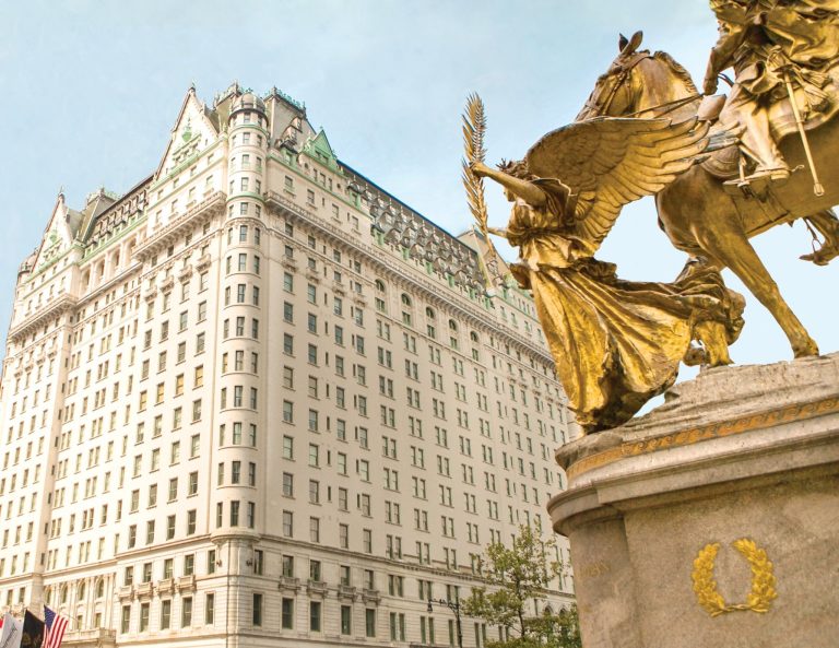 The historic Plaza Hotel features ornate architecture and a golden statue in the foreground against a clear sky.