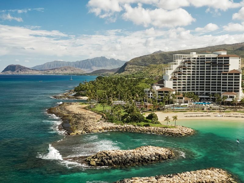 Four Seasons Oʻahu at Ko Olina features lush gardens and a stunning beachfront view surrounded by tropical mountains.