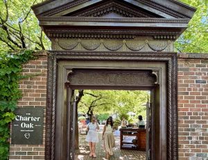 Entrance to The Charter Oak, featuring a decorative archway and guests strolling through the outdoor dining area.