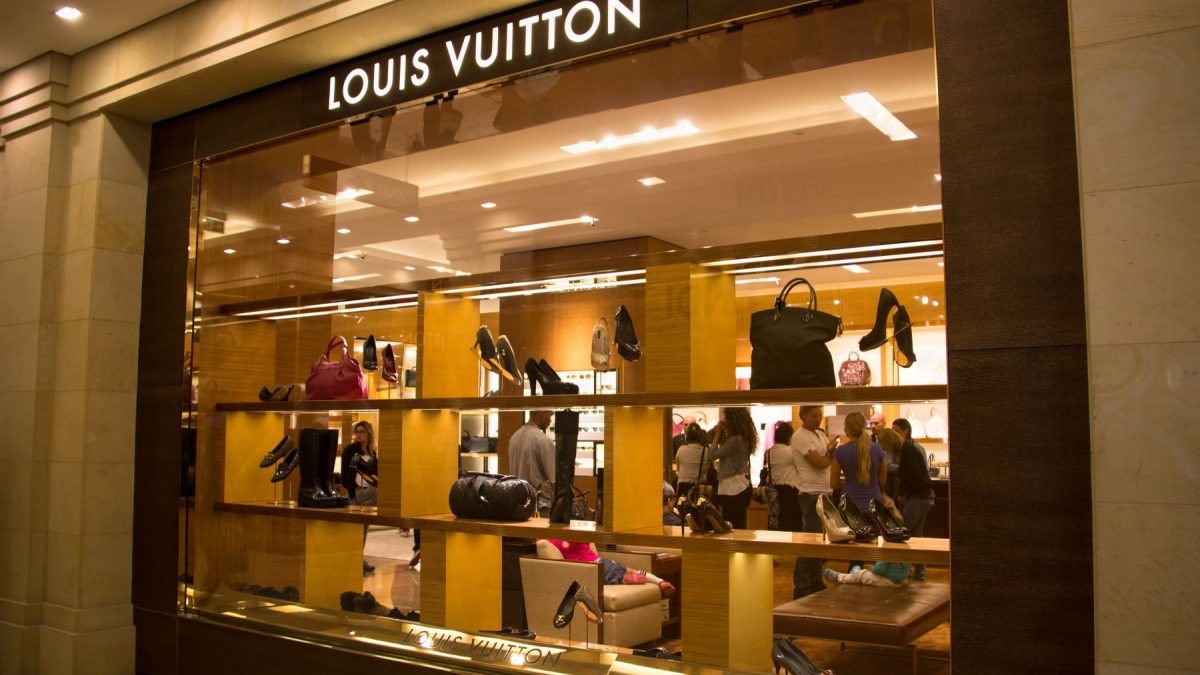Louis Vuitton store display featuring luxury handbags and shoes in a shopping mall setting.